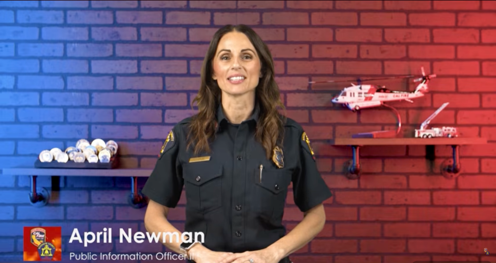Photo of April in a studio with a lower third on the left showing her name and rank